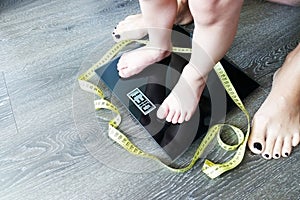 Baby or toddler feet on digital weight scale, mother monitor childÃ¢â¬â¢s diet concept